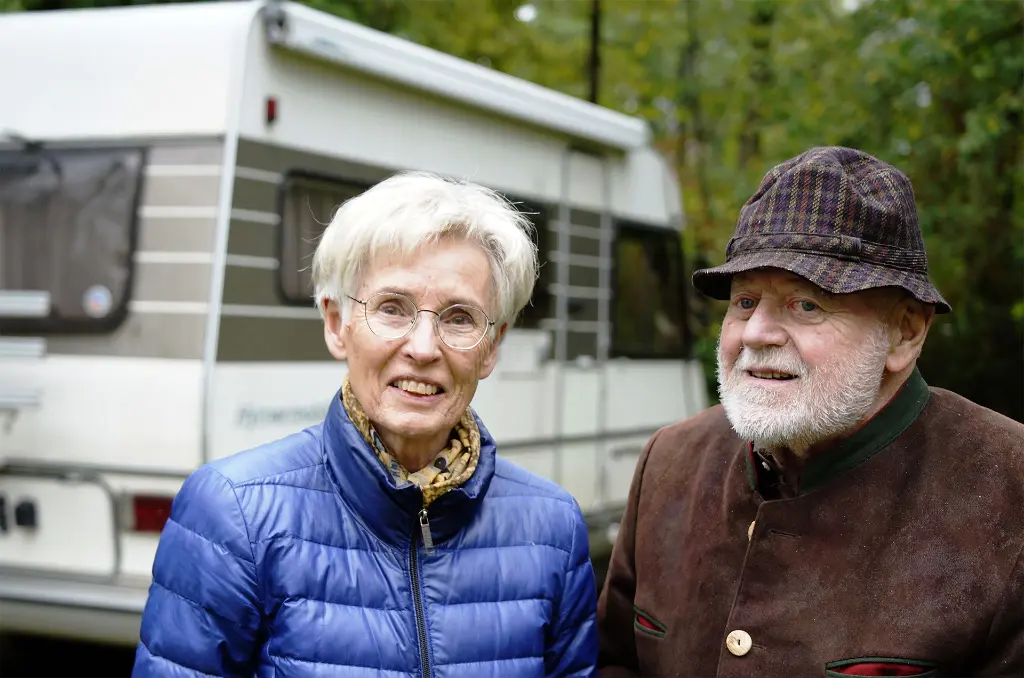 Älteres Ehepaar gemeinsam in ihrem Garten vor einem Wohnmobil