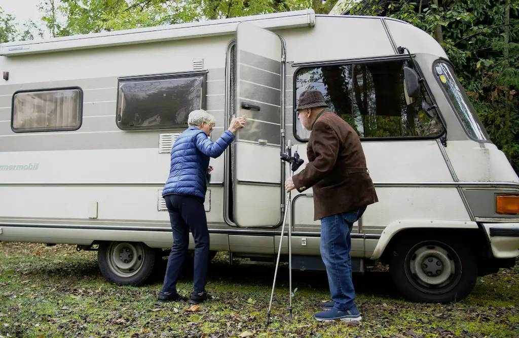 Älteres Ehepaar vor ihrem Wohnmobil. Die Dame öffnet die Türe des Gefährts.