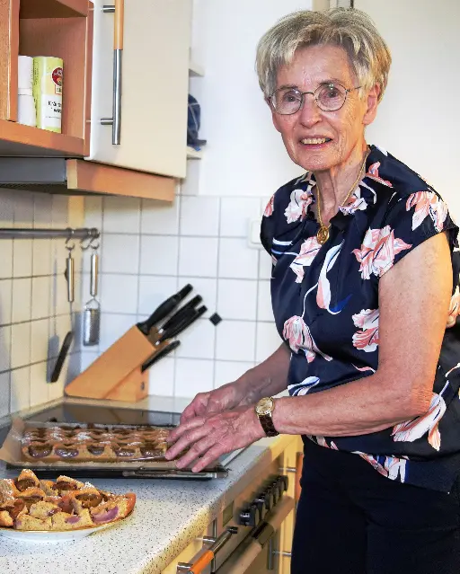 Ältere Dame beim Anrichten von ihrem Kuchen in der Küche