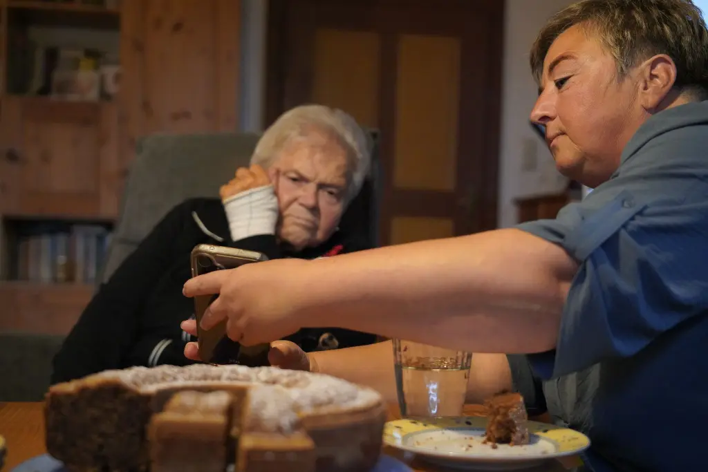 Zwei Frauen sitzen am Tisch, eine zeigt der anderen etwas auf dem Smartphone