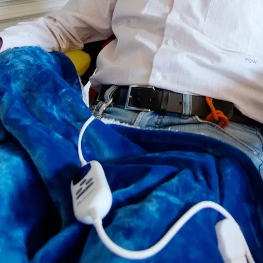 Mann ist mit Heizdecke halb zugedeckt.